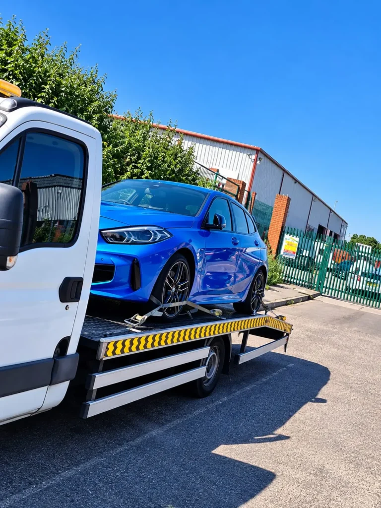 Blue hatchback loaded on a flatbed truck for vehicle transport